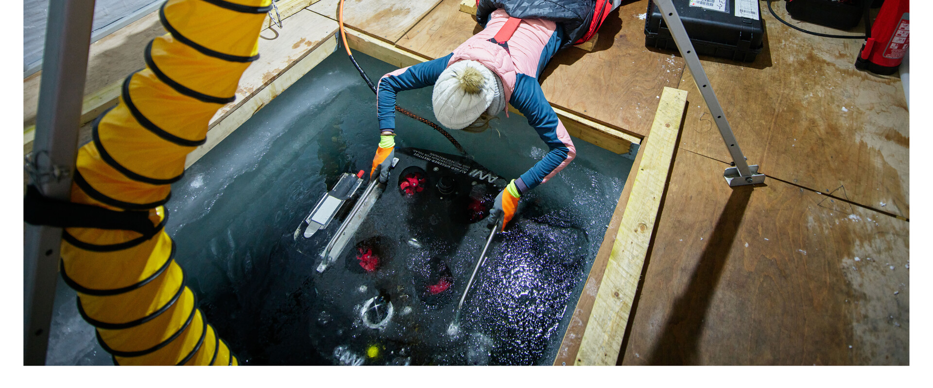 Wissenschaftlerin l&auml;sst Messger&auml;t in ein freigeschnittenes Feld im arktischen Meer hinab.
